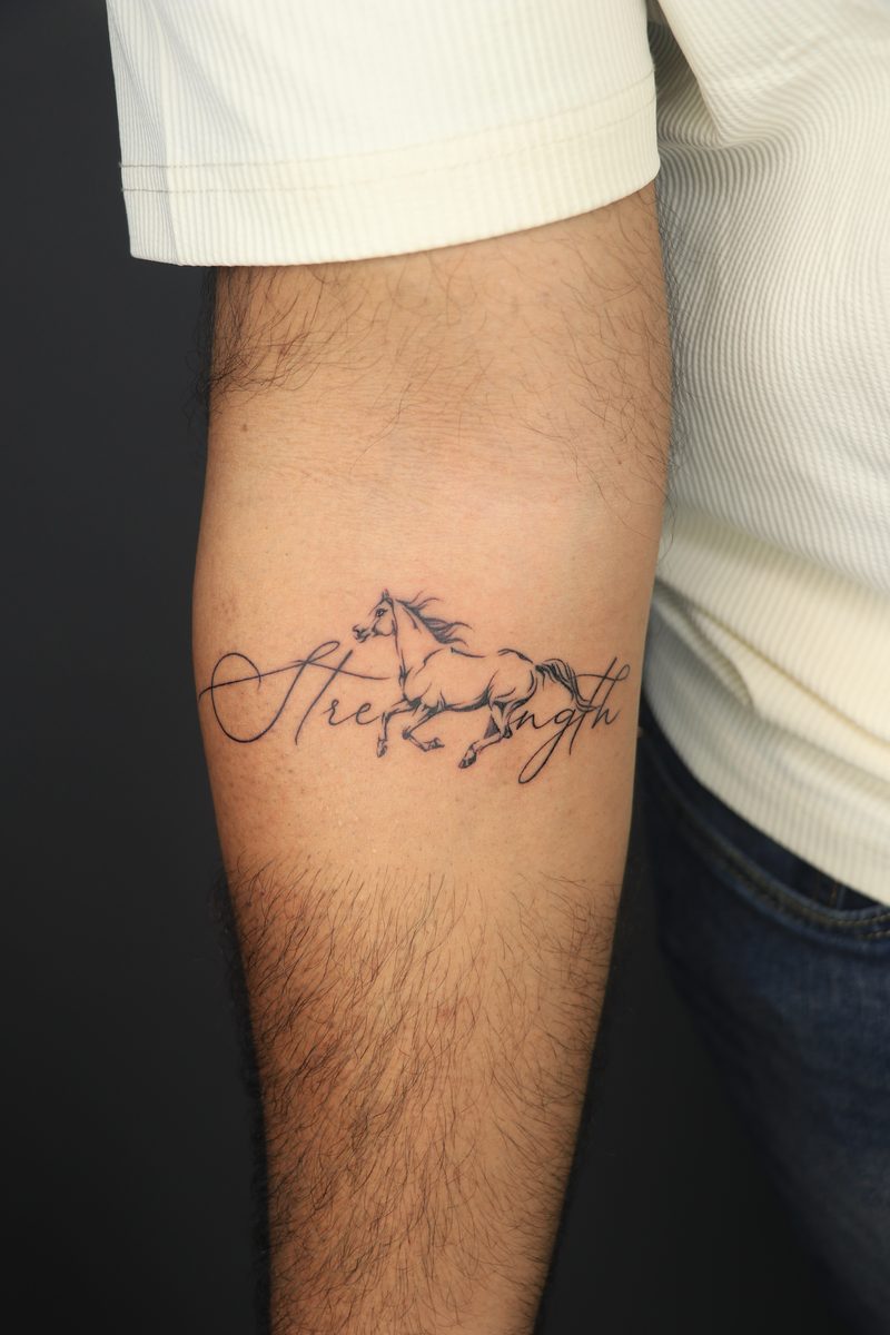 Strength script with running horse fine line tattoo